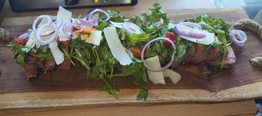 Pièce de bœuf, roquette et parmesan sur planche